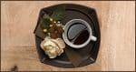 Midjourney: a cup of coffee on a serving platter with a flower and a bow.