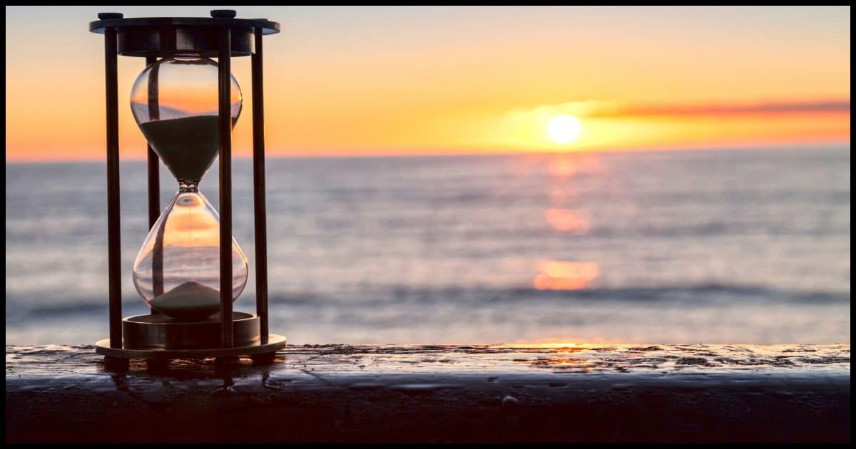 An hourglass in front of a sunset.
